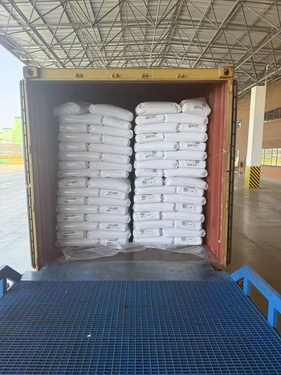 Shipping container at a loading dock with two stacks of 25 kg plastic resin bags