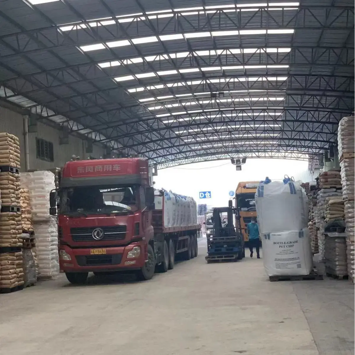 Truck at the loading bay of a resin warehouse with palletized bags and jumbo bags of plastic resin